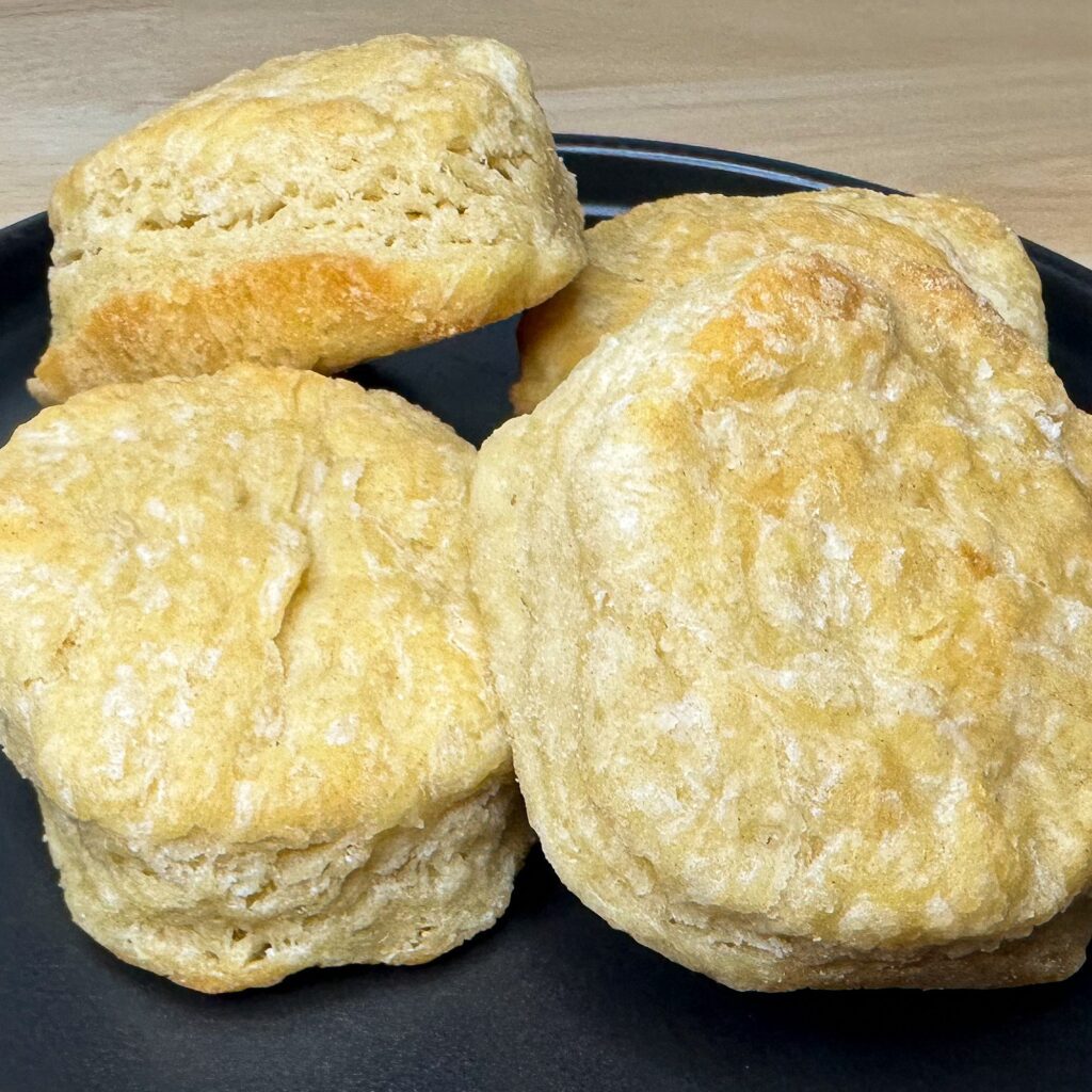 Image of four sourdough biscuits arranged on a black plate.