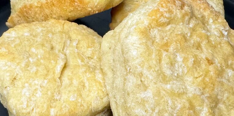 Image of four sourdough biscuits arranged on a black plate.