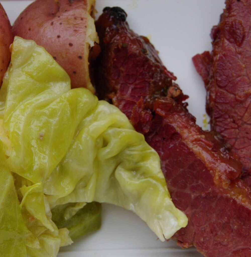 Image of corned beef, cabbage, and red potatoes on a white plate.