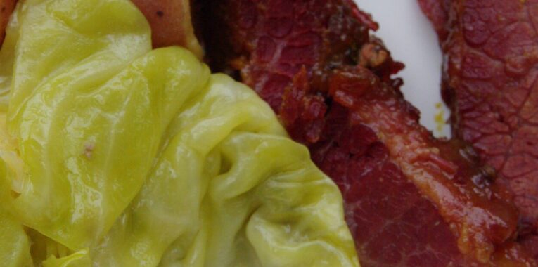 Image of corned beef, cabbage, and red potatoes on a white plate.